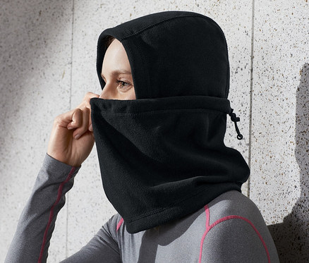 Frau justiert schwarze Microfleece-Sturmhaube am Kopf.