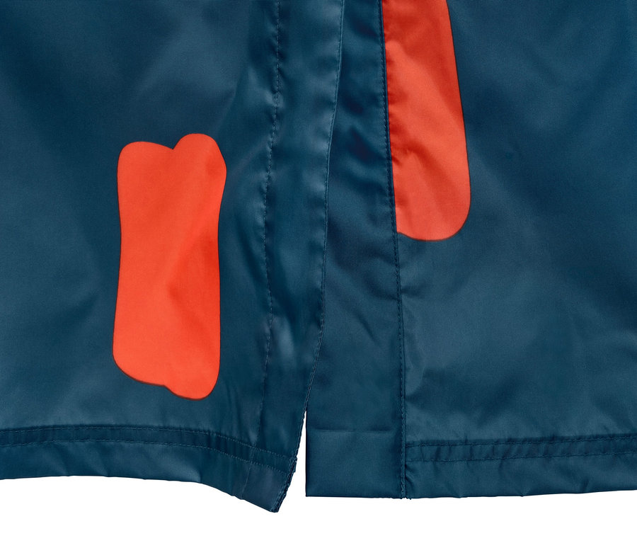 Detailaufnahme eines blauen Regenponchos mit orangefarbenen Flecken und Ärmeln.