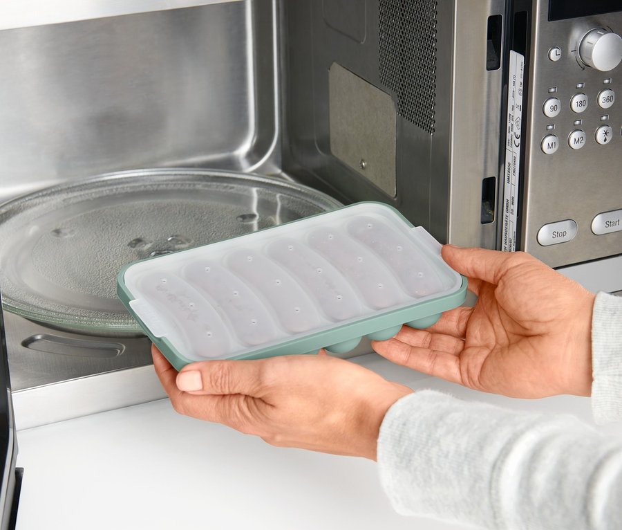 Eine Frau legt einen Mikrowellen-Veggie-Würstchen-Bereiter in eine Mikrowelle.