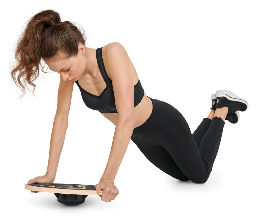 Frau macht Liegestütze auf einem Balance-Board.