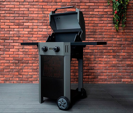 Grauer Buschbeck Elektrogrill »Grenada« mit 2 Brennern auf Holzterrasse vor Ziegelwand.