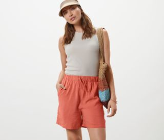 Frau posiert in apricotfarbenen Shorts.