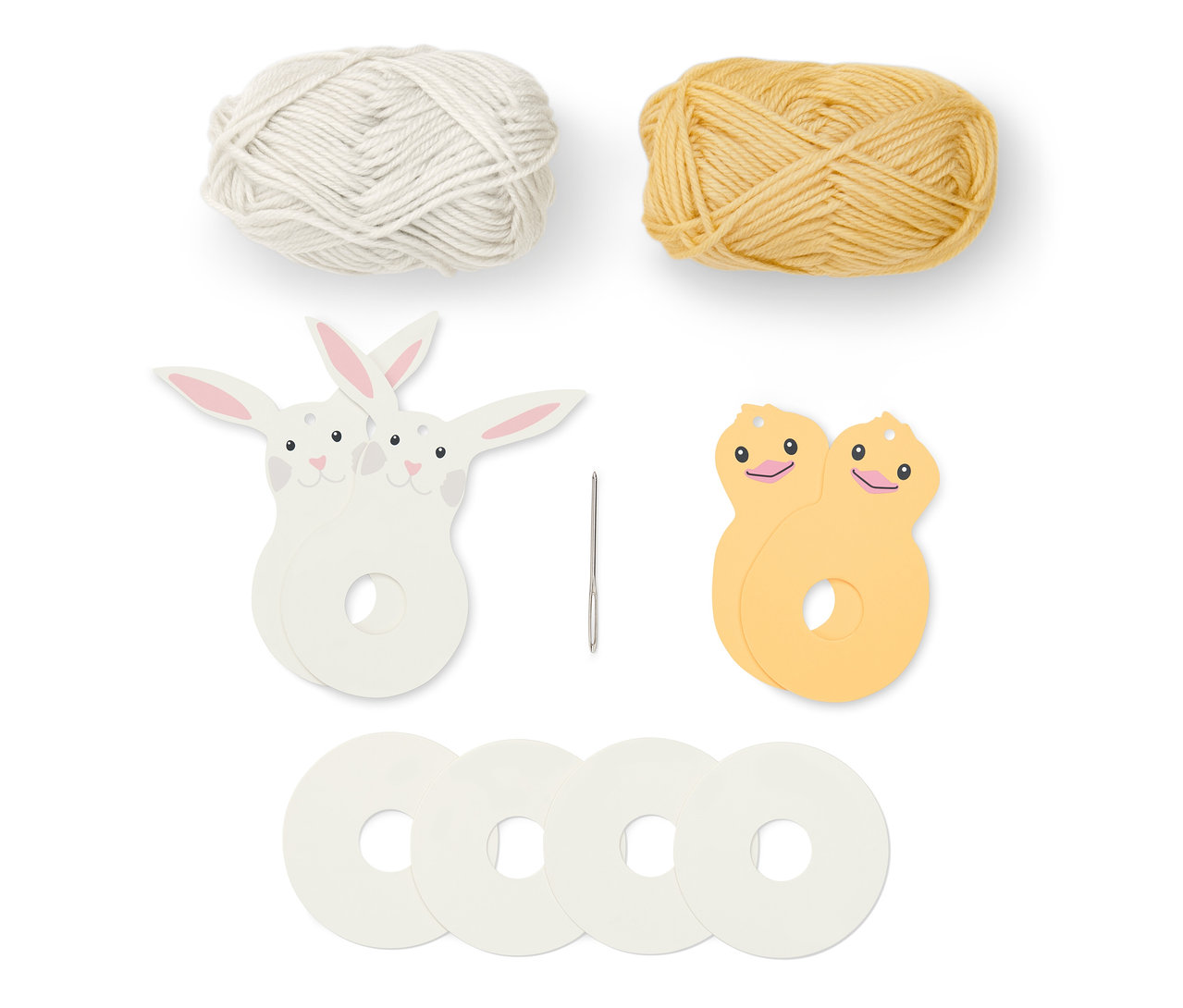 Ein weißes und ein gelbes Wollknäuel, eine Nadel und Teile des Oster-Pompon-Bastel-Sets.
