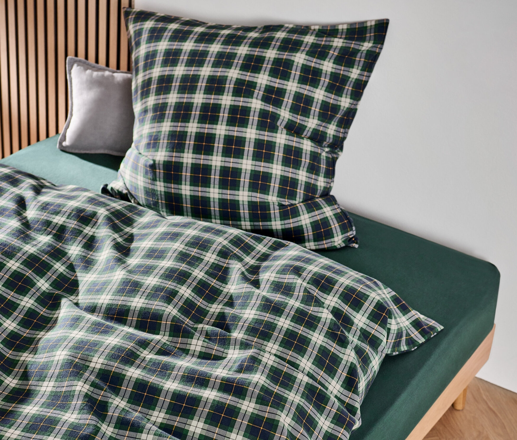 Grün karierte Biber-Bettwäsche in Normalgröße und Übergröße auf einem Bett.