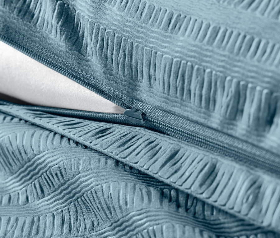 Detailansicht von blauem Seersucker-Bettzeug mit Reißverschluss und weißer Füllung.