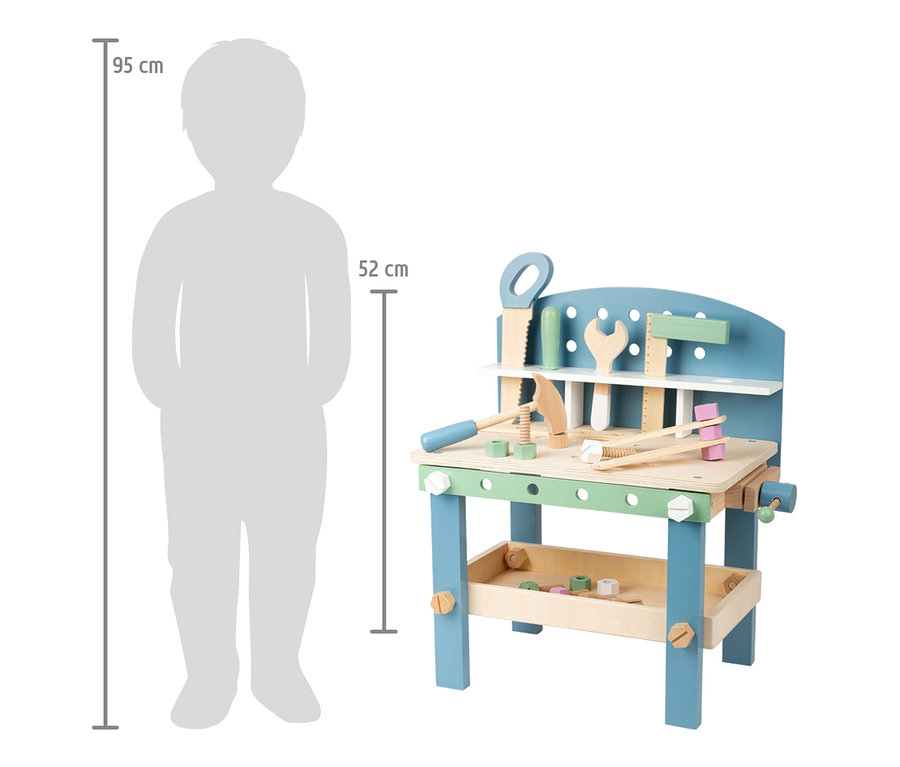 Eine kompakte small foot Werkbank »Nordic« aus Holz mit Werkzeug, daneben eine Kindersilhouette zum Größenvergleich.
