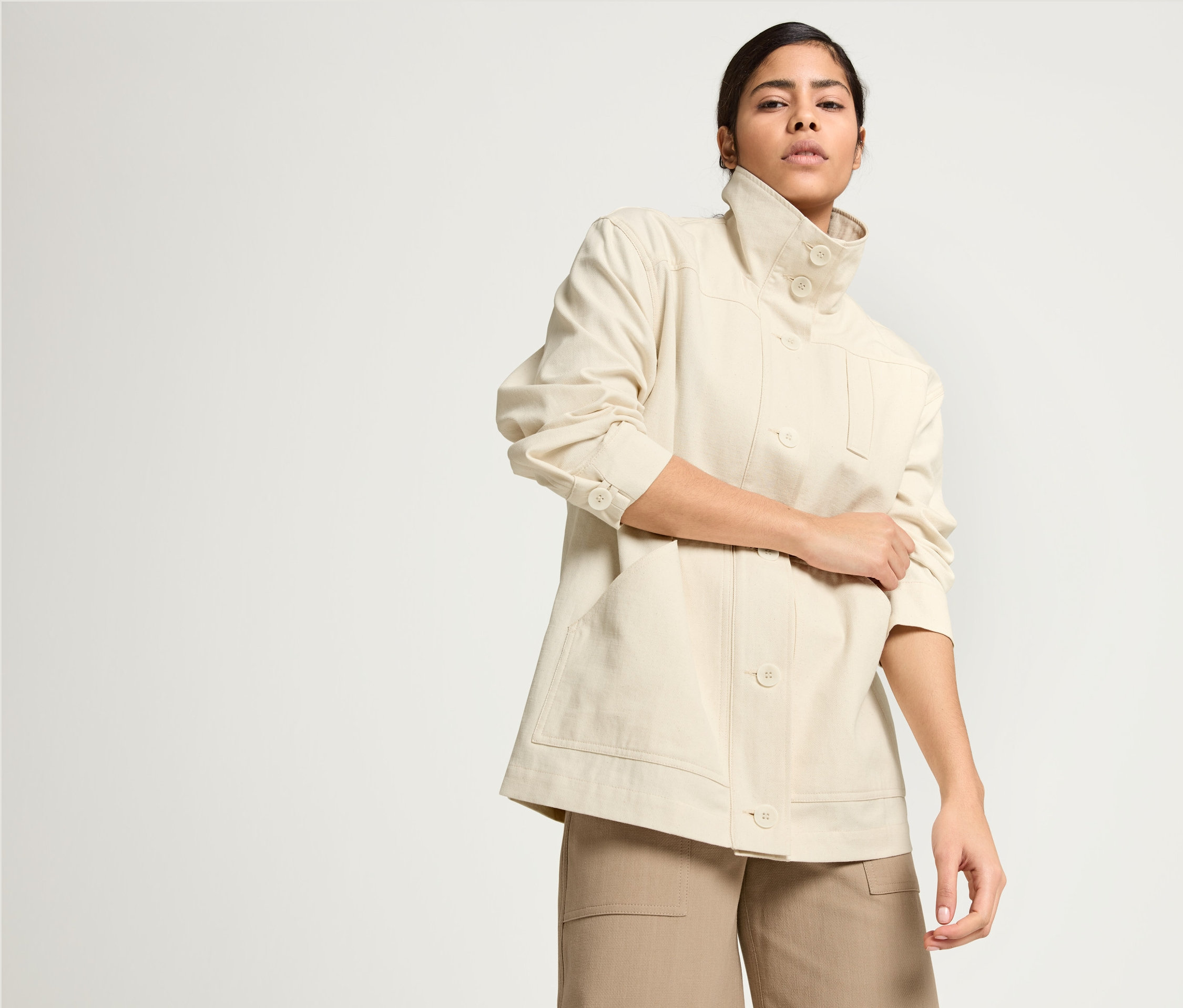 Frau posiert in NAH/STUDIO Parka aus ungefärbter Baumwolle, NAH/STUDIO Culotte aus recycelter Baumwolle und NAH/STUDIO T-Shirt in Ocean Blue.