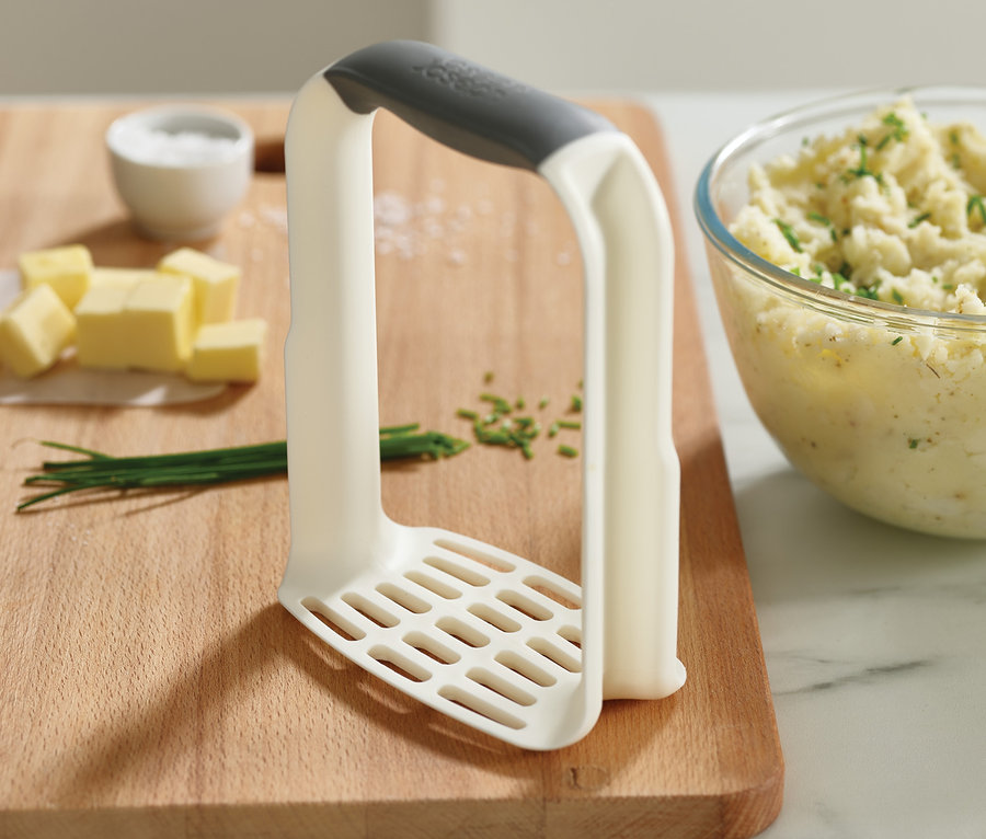 Kartoffelpüree, Butter, Salz und Schnittlauch auf einem Holzbrett mit Joseph Joseph Kartoffelstampfer »Easy-Mash«.