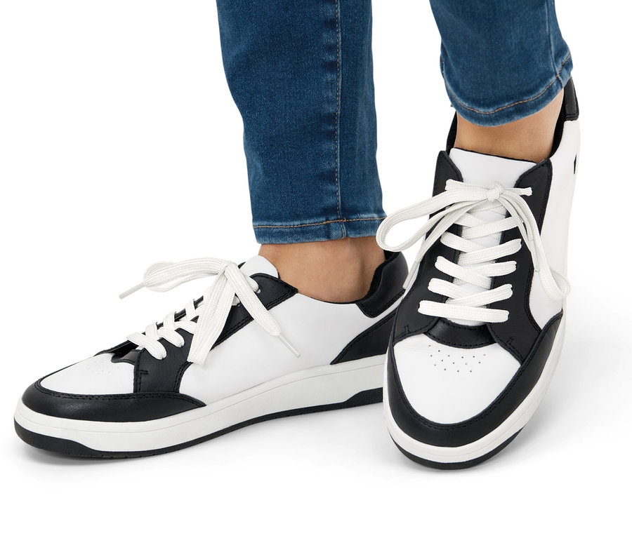 Beine in Jeans und Leder-Sneakern.