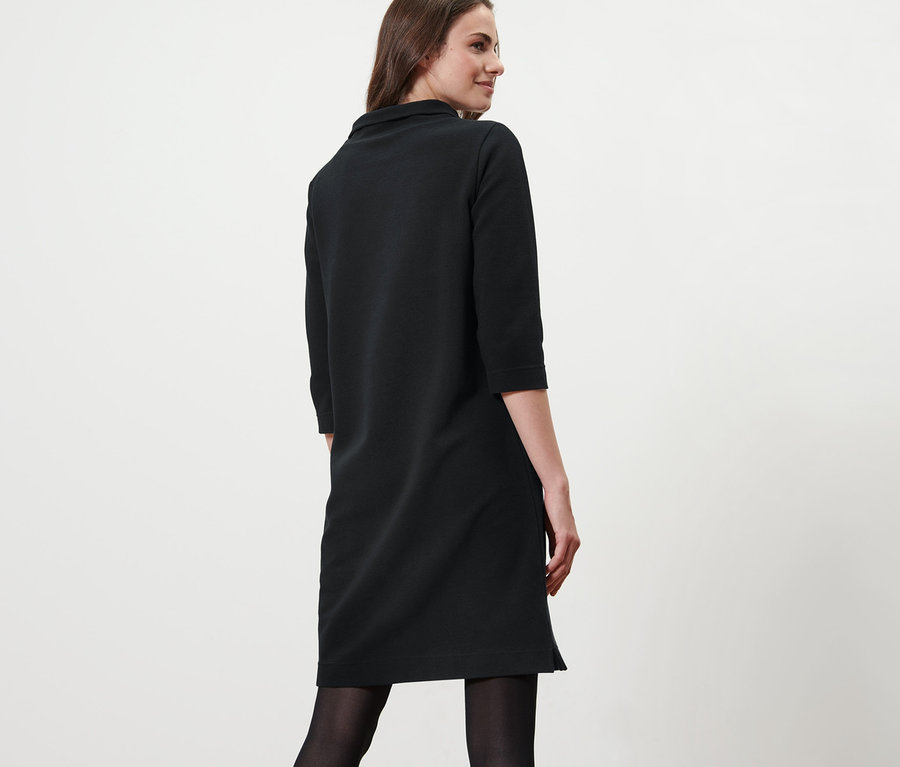 Frau posiert in schwarzem Sweatkleid mit 3/4-Arm.