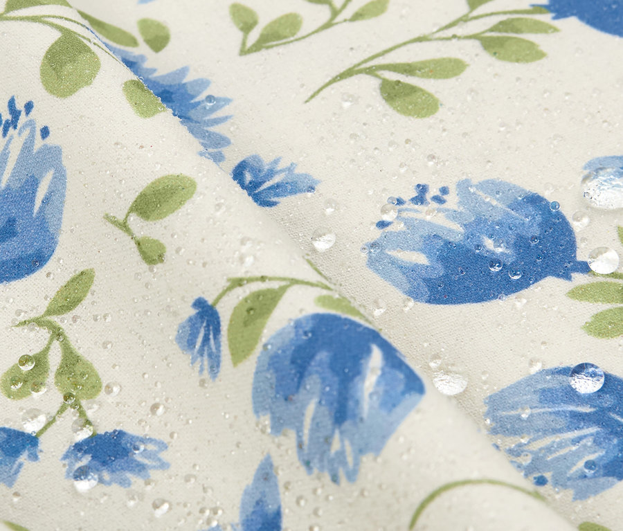 Detailaufnahme einer abwischbaren Tischdecke (ca. 90 x 90 cm) mit blauen Blumen und Wassertropfen.