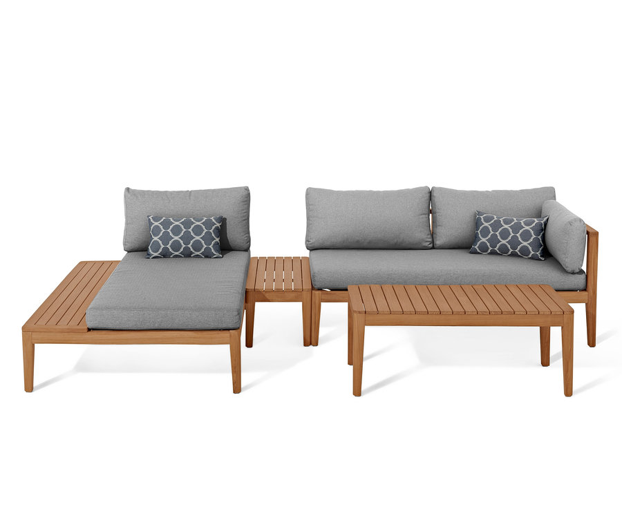 Eine Teak-Lounge-Ecke mit grauen Kissen und einem blauen Dekokissen.