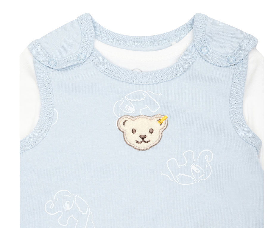 Detailaufnahme eines hellblauen Babybodys mit Teddybär- und Elefantenmotiv. Steiff 2 Baby-Strampler, hellblau ist sichtbar.