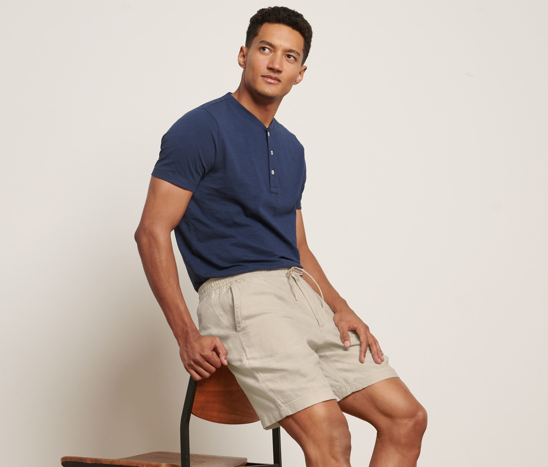 Mann sitzt auf Stuhl und trägt Leinen-Shorts und blaues T-Shirt.