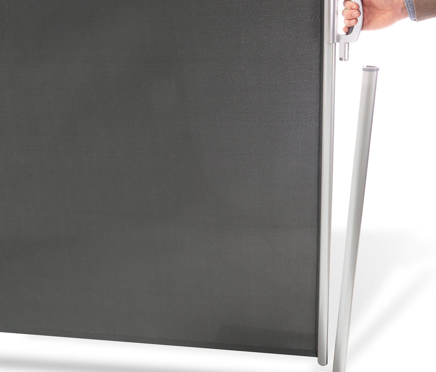 Eine Hand hält den Griff einer grauen Leco Seitenmarkise, 180 x 300 cm.