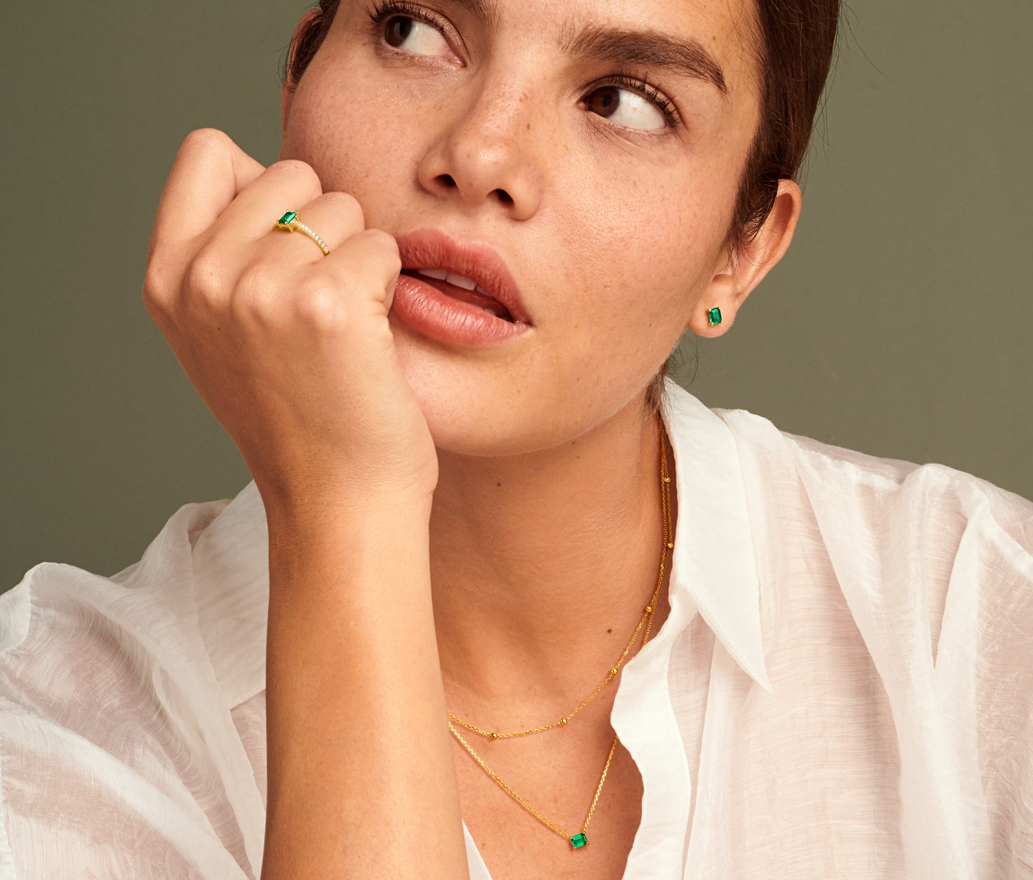 Frau trägt 585 Gold Ring mit grünem Zirkonia, 585 Gold Ohrstecker mit grünem Zirkonia und 585 Gold Kette mit grünem Zirkonia.