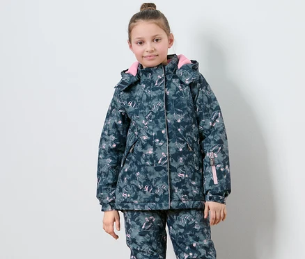 Mädchen posiert in Kinder-Skijacke mit Muster.
