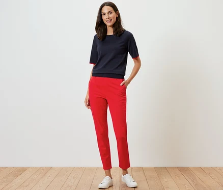 Frau posiert in roter Chino und marineblauem Oberteil.