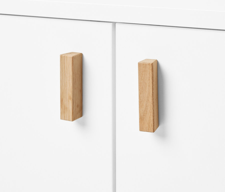 Detailansicht eines weißen Waschbeckenunterschranks mit zwei Türen und Holzgriffen.