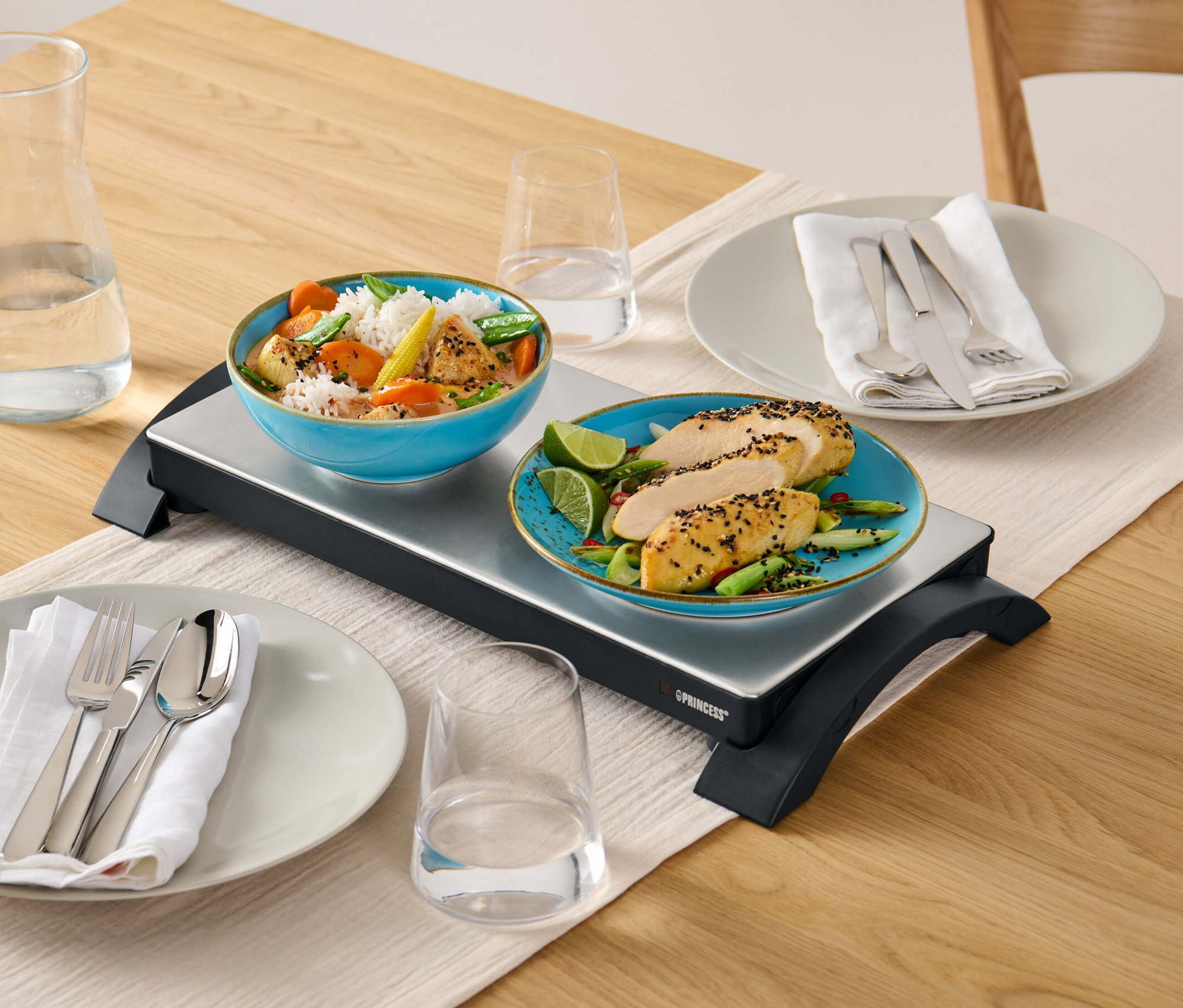 Speisen auf Design-Warmhalteplatte auf Holztisch.