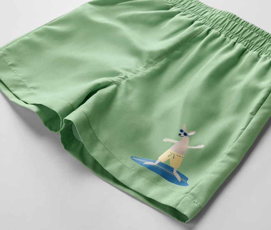 Grüne Kinder-Boardshorts mit Surf-Motiv.