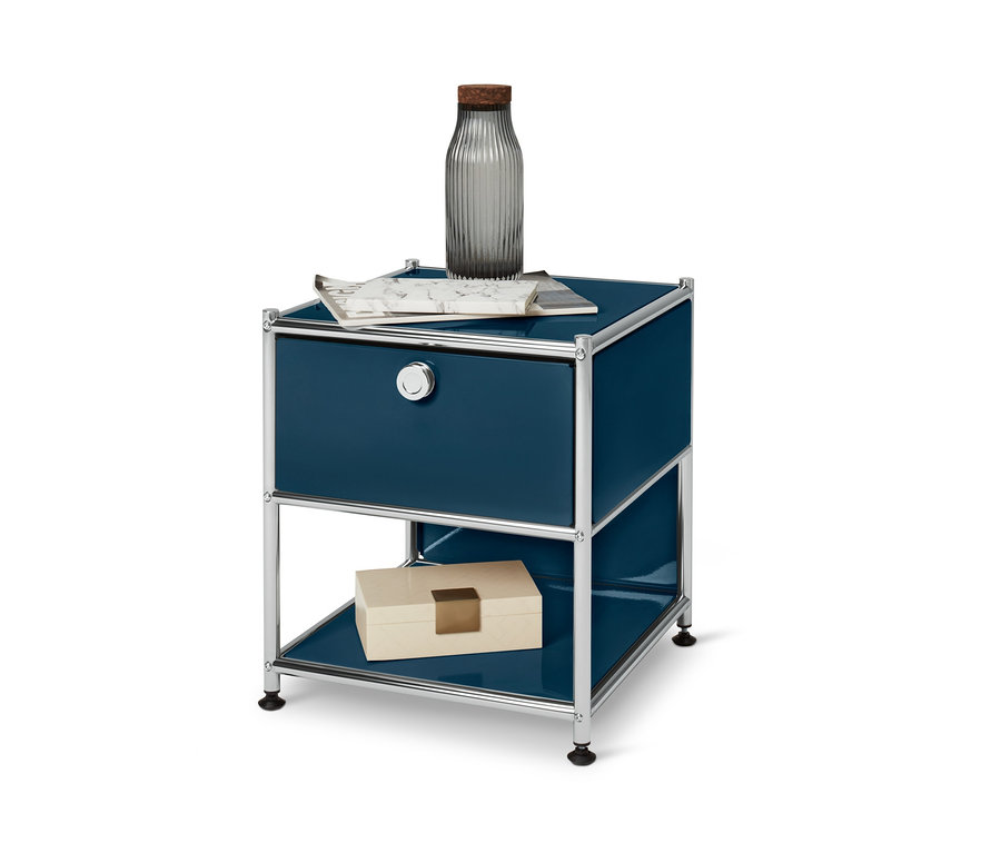 Blauer Beistelltisch »CN3« mit Schublade. Auf der Oberseite befinden sich eine Vase und eine Zeitschrift, auf der Unterseite eine Schachtel.