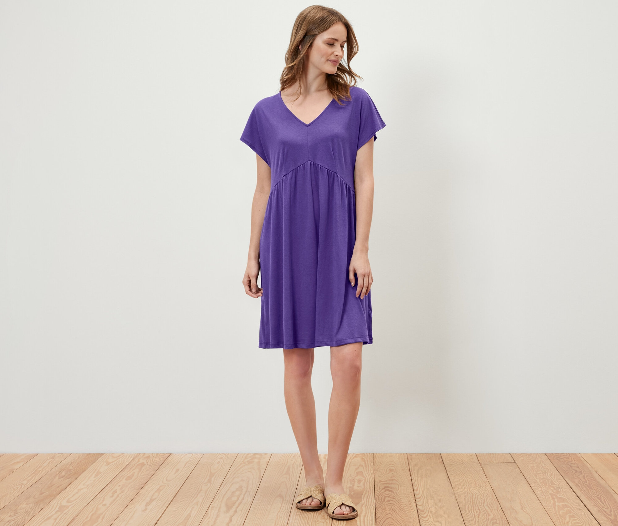 Frau steht und trägt ein lila Jerseykleid.