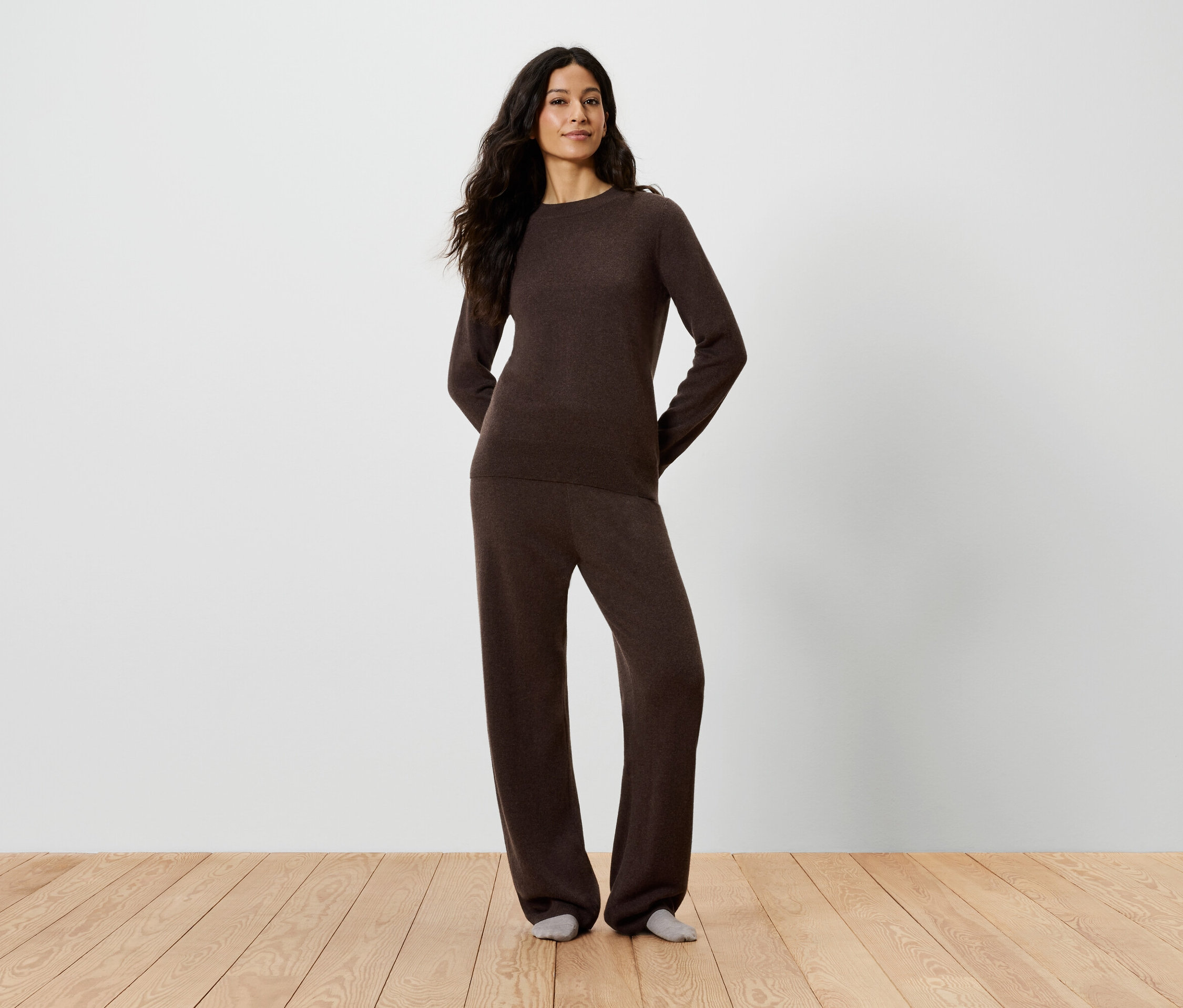 Frau posiert in braunem Pullover und Hose.