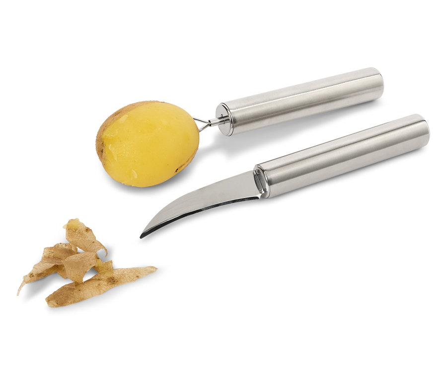 Eine Kartoffel auf einem Schäler und ein Gemüsemesser neben Schalen.