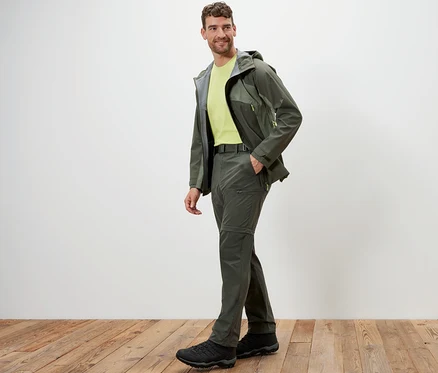 Mann posiert in Khaki 2-in-1-Funktionshose und Jacke auf Holzboden.