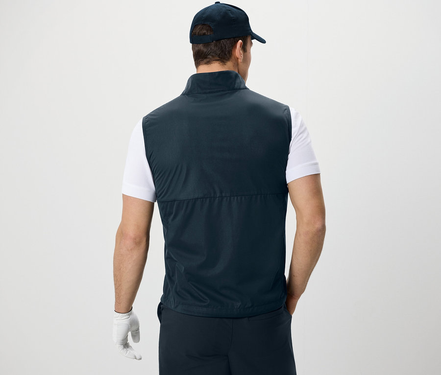 Mann von hinten mit Softshellweste, T-Shirt und Kappe.