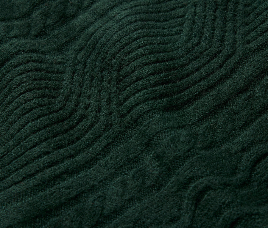 Nahaufnahme eines dunkelgrünen Strickmusters mit erhabenen Wellen.