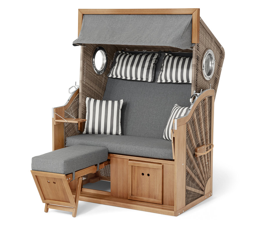 Ein Strandkorb aus Korbgeflecht und Holz mit grauen Polstern und gestreiften Kissen.