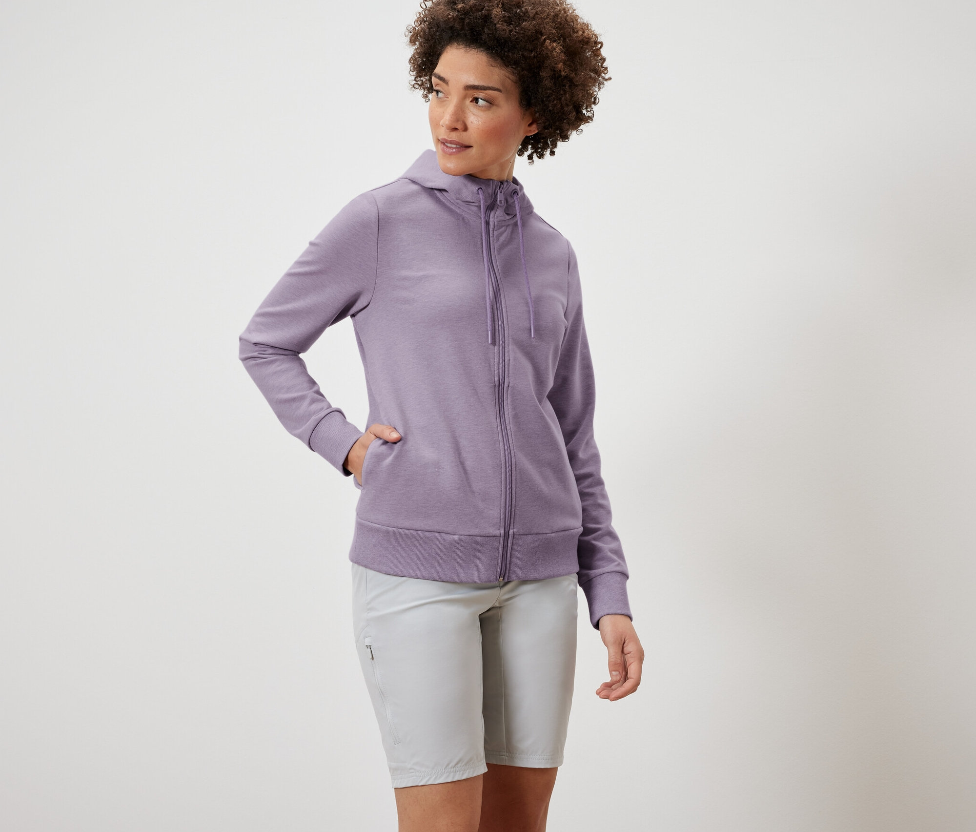 Frau trägt eine lila Sweatjacke und graue Shorts.