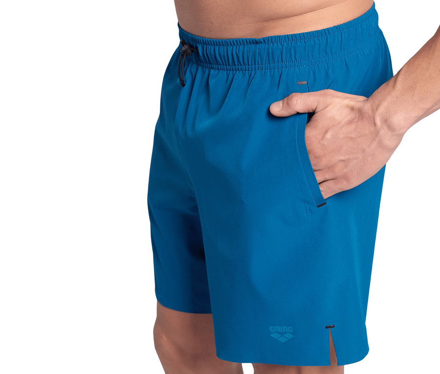Mann hat Hand in Tasche von blauen Badeshorts. Arena Badeshorts Evo, blau.