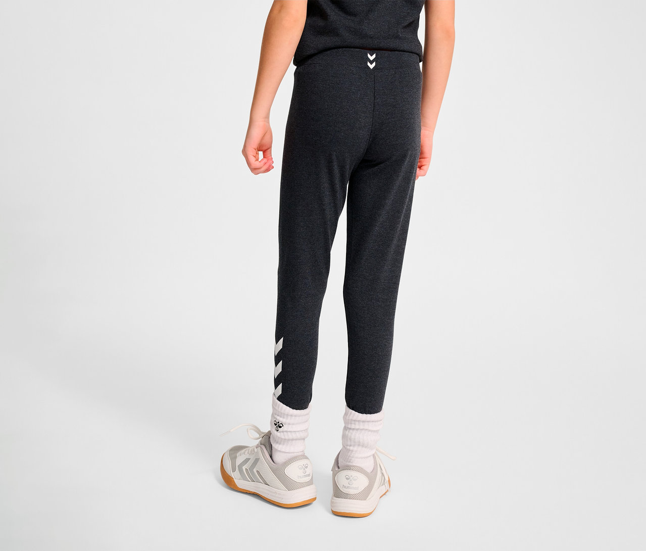 Junge von hinten trägt schwarze HUMMEL HMLJR Logo Tight, Socken und Schuhe.