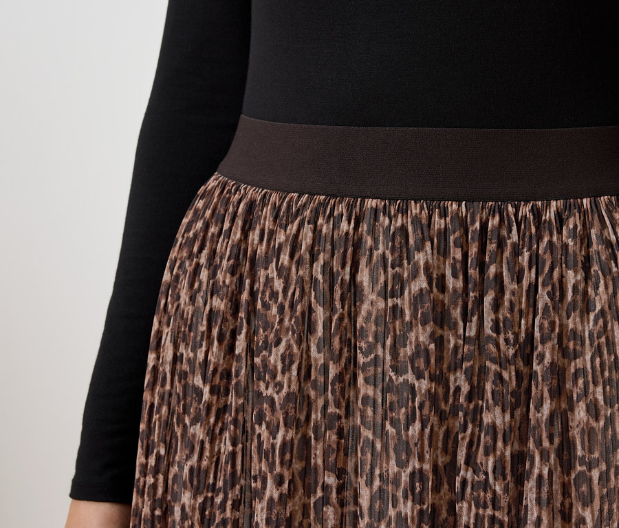 Detailaufnahme eines Damenrocks mit braunem Leopardenmuster und einem schwarzen Langarmshirt.
