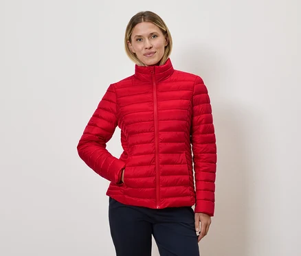 Frau posiert in roter Steppjacke.