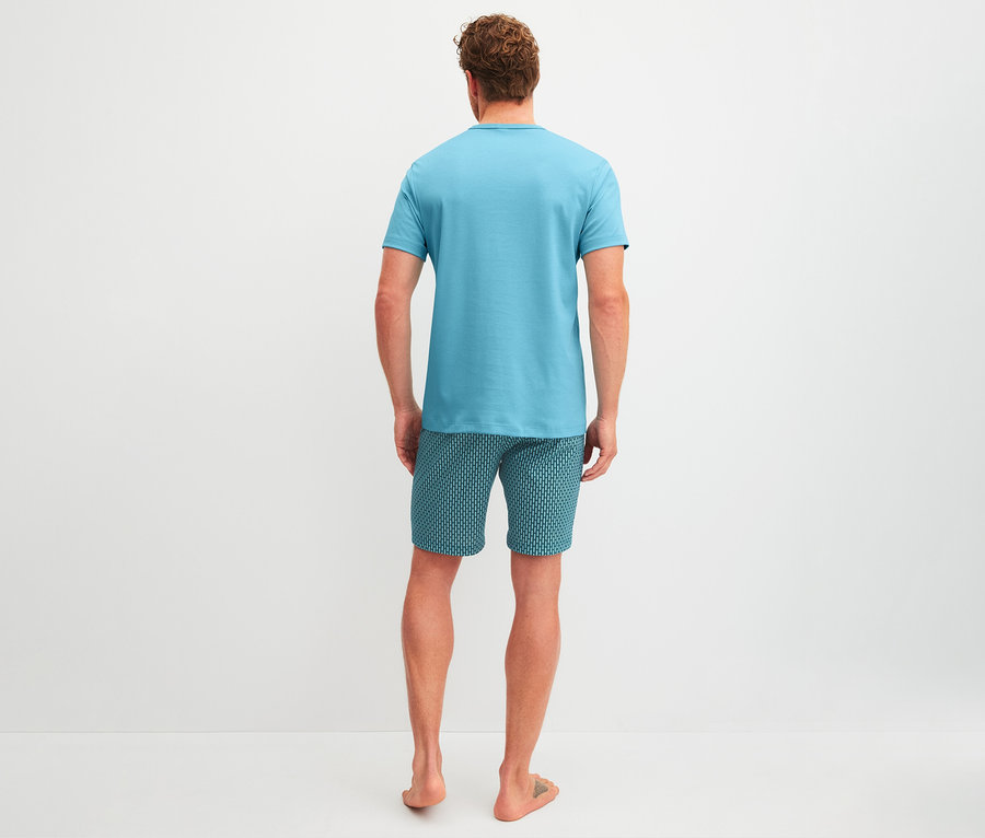 Mann von hinten in blauem T-Shirt und gemusterten Shorts.