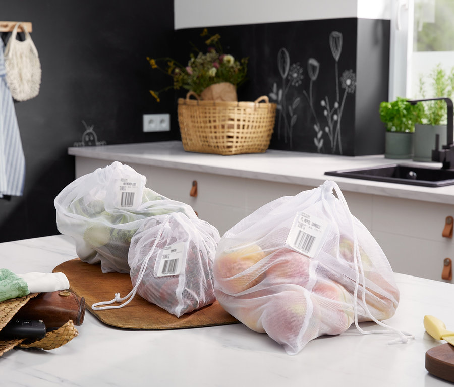 Drei mit Produkten gefüllte 4 Obst- und Gemüsenetze liegen auf einer Küchentheke.