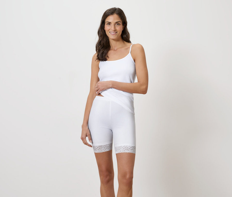 Frau trägt ein weißes Tanktop und kurze Leggings mit Spitzenbesatz.