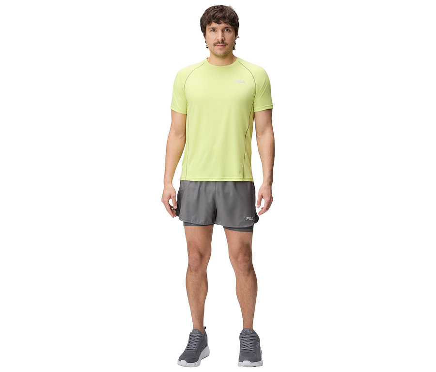 Mann steht und trägt ein hellgrünes T-Shirt, graue Shorts und graue Turnschuhe.