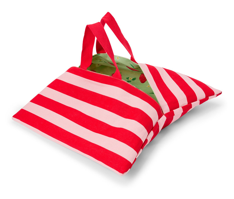 Eine rot-weiß gestreifte Tasche mit roten Henkeln und einem grünen Innenfutter mit Erdbeermuster liegt auf einer weißen Oberfläche.