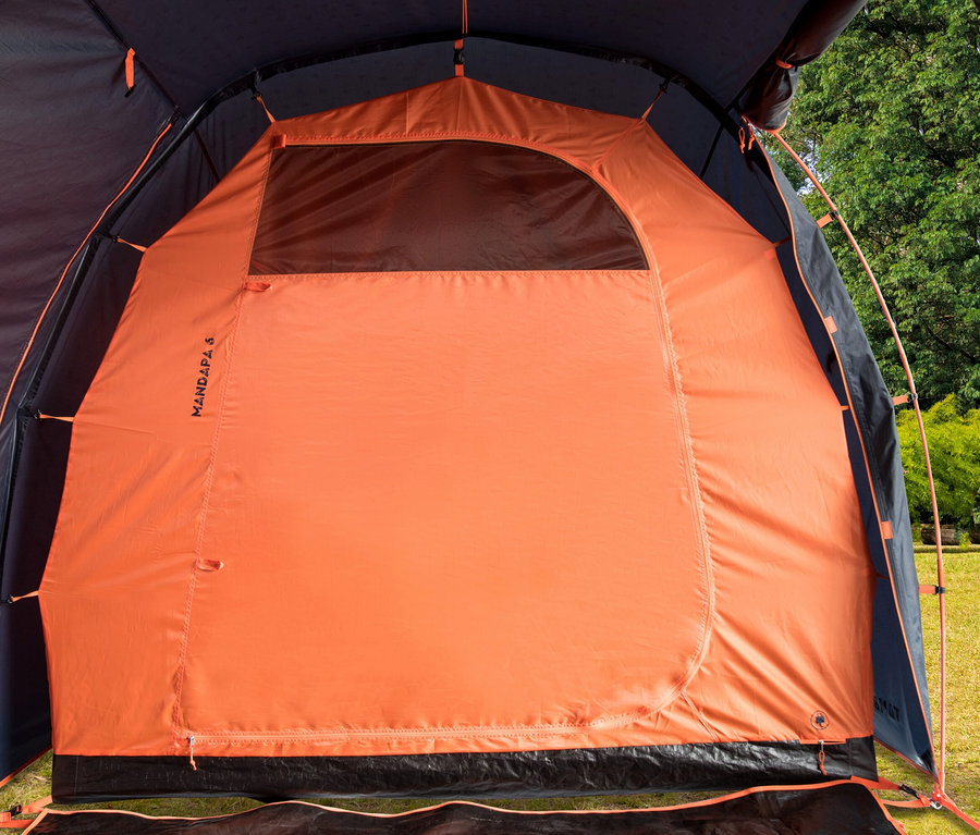 Innenansicht eines orangefarbenen Mandapa 6 Zelts mit schwarzem Boden und Fenster, im Hintergrund Bäume.