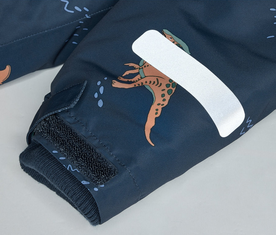 Nahaufnahme eines marineblauen Ärmels mit Dinosaurier-Muster, Klettverschluss und reflektierendem Streifen.