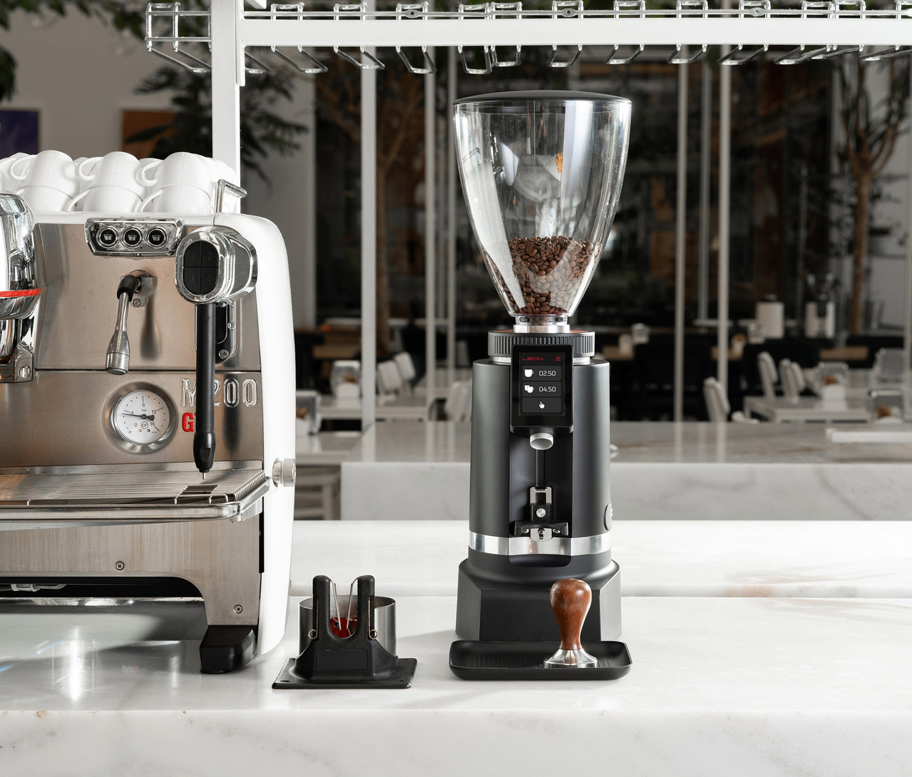 Eine Kaffeemühle steht neben einer Espressomaschine auf einer Marmoroberfläche.