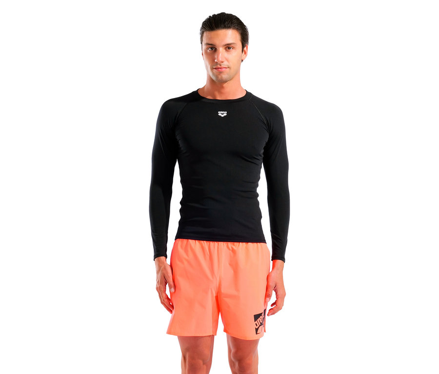 Mann steht, trägt ein schwarzes langärmeliges Shirt und orangefarbene Shorts.