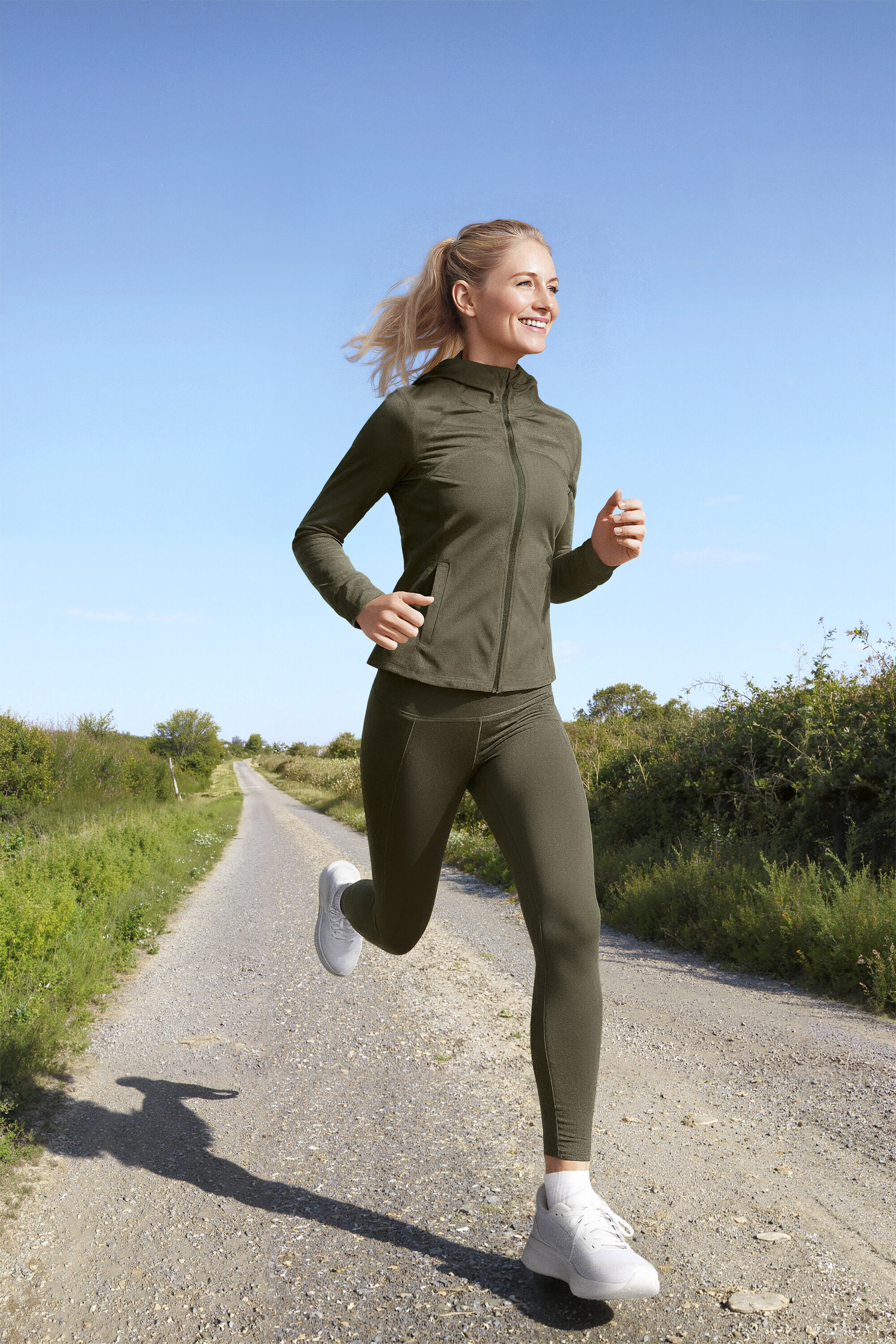 Frau läuft auf einem Feldweg, sie trägt eine Sportjacke, eine Sportleggings »ActivePower« und ein Sportshirt in Lime.