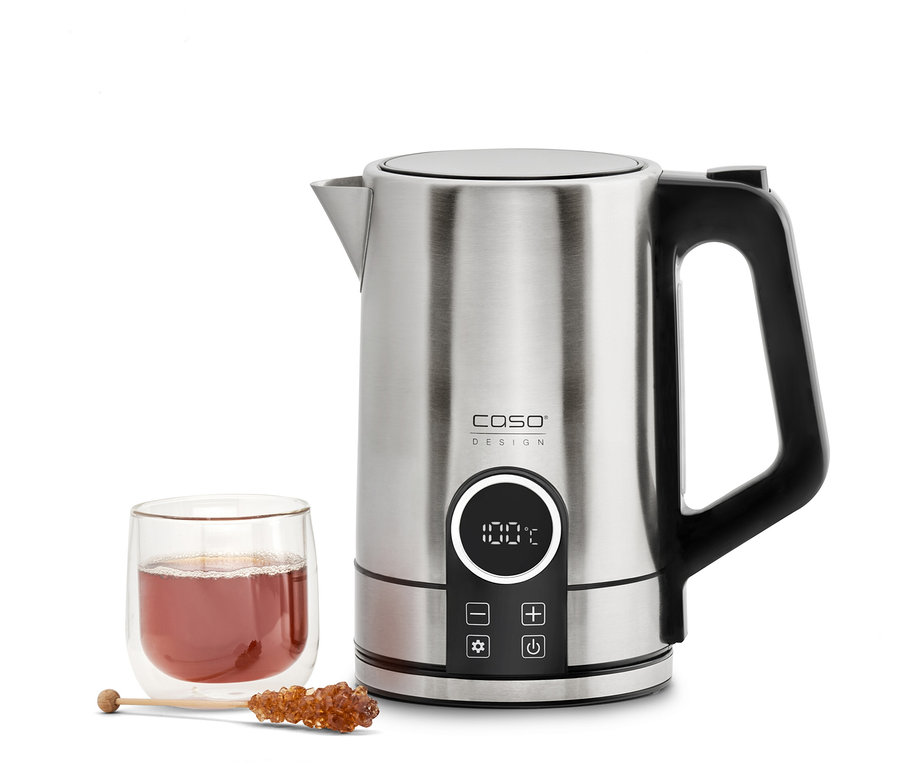 Ein silberner Wasserkocher steht neben einem Glas Tee und einem Kandisstäbchen.