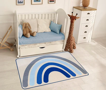 Ein blau gestreifter Kinderteppich »Rainbow« liegt in einem Kinderzimmer mit einem weißen Kinderbett und einer Spielzeuggiraffe.